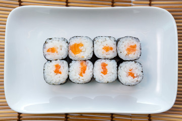Syake roll with salmon. Hosomaki thin rolls, simple rolls, small rolls, with cucumber. top view on a white plate.