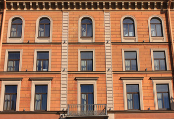 Fototapeta na wymiar Building facade architecture of old residential house outside. Multi-story old facade, brown color walls with simple windows in row. Apartment exterior close up, classic european house close up view