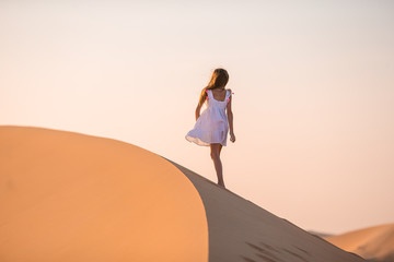 Fototapeta na wymiar Girl among dunes in desert in United Arab Emirates