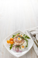 Tuna salad with rice, arugula and tomatoes on light wooden background. Healthy food, seafood menu,