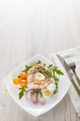 Tuna salad with rice, arugula and tomatoes on light wooden background. Healthy food, seafood menu,