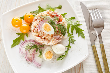 Tuna salad with rice, arugula and tomatoes on light wooden background. Healthy food, seafood menu,