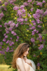 Beautiful girl in a vintage dress in spring lilac garden