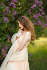 Fototapeta na wymiar Beautiful girl in a vintage dress in spring lilac garden