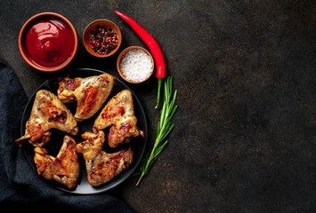 Grilled chicken wings on a plate with spices on a stone background with copy space for your text