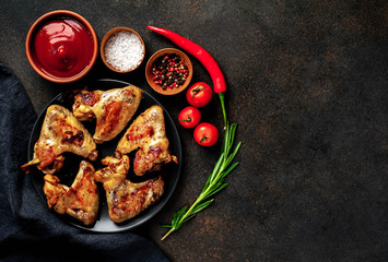 Grilled chicken wings on a plate with spices on a stone background with copy space for your text