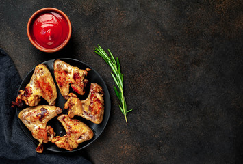 Grilled chicken wings on a plate with spices on a stone background with copy space for your text