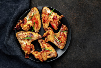 Grilled chicken wings on a plate with spices on a stone background 