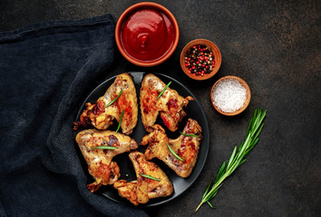 Grilled chicken wings on a plate with spices on a stone background 