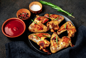 Grilled chicken wings on a plate with spices on a stone background 