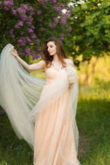 Obraz na płótnie Canvas Beautiful bride in a vintage dress in spring lilac garden