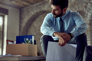 Displeased businessman sitting in the office after being fired.