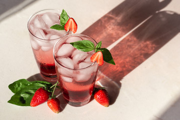 Cold summer strawberry basil lemonade in glass with long shadows 