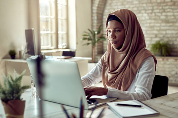 Black Islamic businesswoman working on a computer in the office.