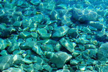 Fototapeta na wymiar Full frame of pebbly sea bottom turquoise colored.