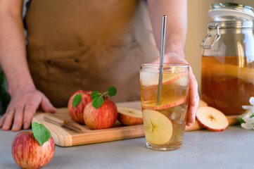A man in an apron preparing a drink kombucha iced tea. Fermented probiotic refreshing kombucha or apple cider in a glass. Horizontal orientation.