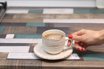 Female hands hold a coffee mug or cup on a colorful table. copy space. selective focus