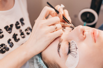 Obraz na płótnie Canvas Beauty Salon - Sticking Artificial Eyelashes on the Eyelids in Bundles - Eyelash Extensions