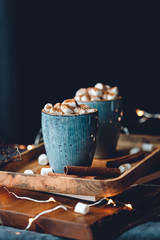 Hot chocolate with marshmallow and cinnamon in blue ceramic cups on a table. The concept of cosy holidays and New Year.