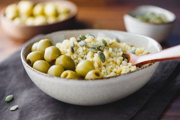Bulgur with green olives and pepitas, healthy nutrition easy recipe from long-stored food.