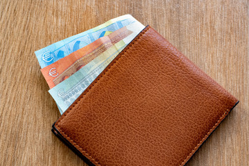 New leather wallet with euro money on a wooden background