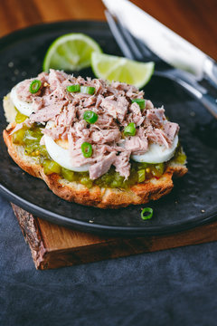 Open sandwich with canned tuna, egg and pickled cucumber dressing served with lime.