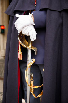 A guard of the Italian Corps of Cuirassiers stands with a sword in his hand in white gloves. Closeup.
