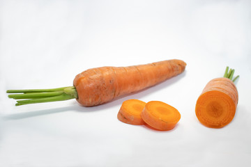 Close up view of a sliced and a whole piece of carrot isolated on a white background. Space for copy