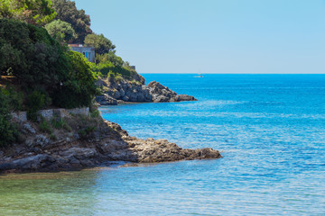 Fototapeta na wymiar Seashore coastline with cliff and rocks on a mountain slope. Blue sea of the Island of Elba in Italy in the Tuscany region. Crystal clear sea. Mediterranean Sea