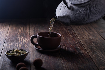 Traditional asian tea ceremony, the process of brewing tea, warm soft light, a dark background.
