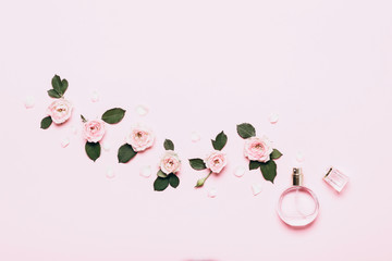Bottle of perfume and flower arrangement of rosebuds on pink background - obrazy, fototapety, plakaty