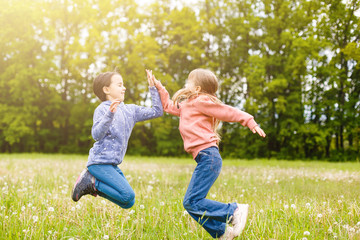 Fototapeta premium Two sisters hug one another outdoors, happy family