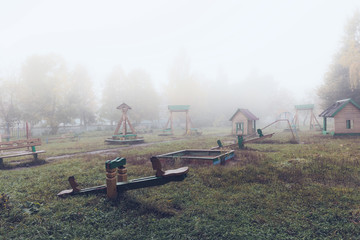 Playground in a small town in the early autumn morning. Heavy fog.