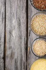 Millet, buckwheat and rice in glass bowls on a wooden table