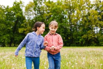 Fototapeta premium Two sisters hug one another outdoors, happy family