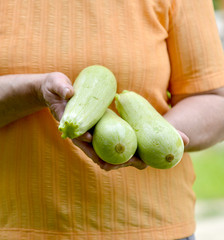 woman holding zucchini, in hand