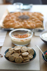 Table setting with colorful dishes and various food: crackers, hummus, homemade bread, cake, strawberries and whipped cream. Selective focus.