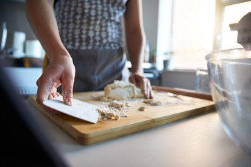 Fototapeta na wymiar Woman using a dough scraper, making fresh dough at home.
