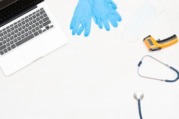 Top view of the doctor's workplace with a stethoscope, infrared thermometer, protective mask,...