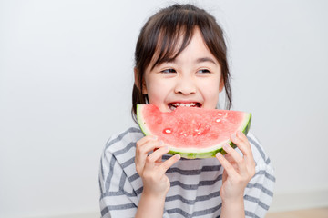 Asian little girl eating watermelon at home