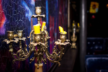 vintage candlesticks with yellow candles. It stands next to an old picture. Photo in dark shades. Design of a modern cafe