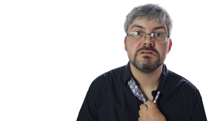 A drunk man pulls a tie. Dark shirt. Glasses on the face. Unshaven. Bright room. Crisis time. Work at home. Remote work.