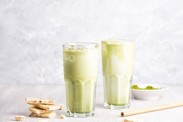 Glasses of matcha latte with coconut milk and white chocolate on wooden and marble background