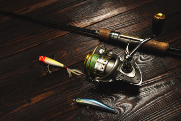 Fishing tackle spinning fishing rod with lures spoon wobbler popper hooks on darken wooden...