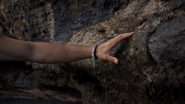 European man walks among the rocks and touches them with his hands