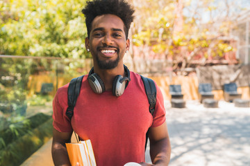 Afro university student holding his books.