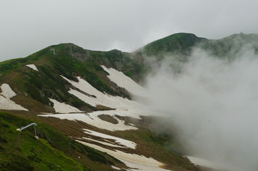 Fototapeta na wymiar Snow in the mountains in summer, cloudy weather