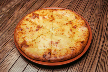 Top view on tasty traditional megrelian khachapuri - pie with melted salt cheese suluguni and egg yolk on wooden tray. Traditional georgian food