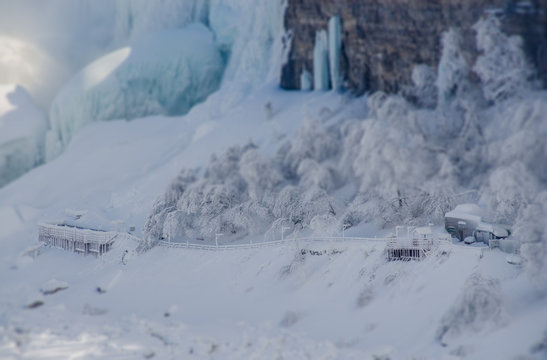 frozen buildings at base of waterfall in winter