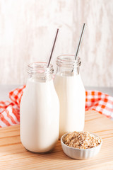 Non dairy oat milk in glass bottles with reusable metal straws. Healthy vegan milk alternative still life, copy space. Substitute for traditional cow milk with oat flakes, healthy lifestyle concept